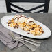 An oval Libbey porcelain tray with waffles and ice cream topped with chocolate sauce.