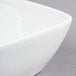A close-up of a Libbey white porcelain square bowl with a curved edge.