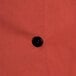 A close up of a black button on a spice orange Chef Revival chef jacket.