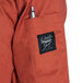 The back pocket of a spice orange Chef Revival jacket with a pen in it.