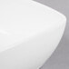 A close up of a Libbey white porcelain square bowl with a curved edge.
