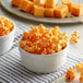 A bowl of Grandma Jack's Gourmet Gold Cheddar Popcorn on a table with cheese cubes and crackers.