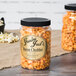A jar of Grandma Jack's Gourmet Bacon Cheddar Popcorn on a table with a label.