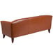 A Flash Furniture brown leather sofa with wooden legs.