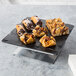 An Elite Global Solutions black faux slate melamine tray with pastries on it.