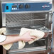 A person using a towel to open an Alto-Shaam Undercounter Cook and Hold Oven.