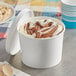 A white Choice paper food container filled with white and brown ice cream and cookies.