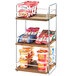 A Cal-Mil three tier wood and chrome merchandising shelf with food on it.