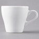 A close-up of a Tuxton white porcelain espresso cup with a handle.