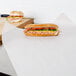 Choice newsprint sandwich wrap paper wrapped around a sandwich on a cutting board.