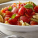 A bowl of pasta with Furmano's diced tomatoes and basil on a table.