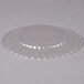 A WNA Comet clear plastic plate with a scalloped edge.