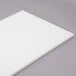 A white plastic Avantco cutting board on a gray surface.