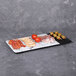 An Elite Global Solutions rectangular faux slate and marble serving board with meat and vegetables on it.