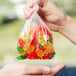 A hand holding a LK Packaging plastic food bag filled with gummy bears.