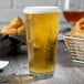 An Anchor Hocking rim tempered mixing glass filled with beer sits on a table.
