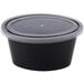 A Newspring black oval souffle container with a clear lid.