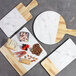 An Elite Global Solutions rectangular faux alder wood and marble melamine serving board with handle holding cheese and nuts.