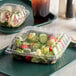 A salad in a Dart clear plastic hinged container on a tray.
