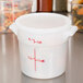 A white plastic Cambro food storage container with measurements on it.