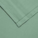 A close up of a seafoam green fabric with a white hemmed border.