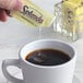 A hand pouring a Splenda packet into a cup of coffee.
