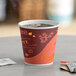 A close up of a Choice 8 oz. tall coffee paper cup filled with coffee on a table.