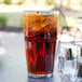 A GET clear plastic tumbler filled with iced tea on a table on an outdoor patio.