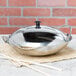 A silver Thunder Group stainless steel wok serving dish with a lid on a bamboo mat.