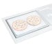 A Vollrath stainless steel sheet pan adapter plate on a counter with two pizzas on it.