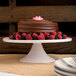An Elite Global Solutions faux Carrara marble round plate stand holding a chocolate cake on a table in a bakery.