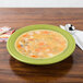 A Lemongrass Fiesta china rim soup bowl filled with soup on a table.