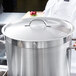 A chef using a Vollrath Centurion stainless steel domed cover on a large pot.