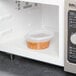 A Pactiv translucent plastic deli container of beans in a microwave.