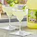 Two glasses of Finest Call Margaritas with lime slices on a table.
