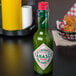 A green TABASCO® hot sauce bottle with a red lid on a table.