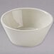 A Tuxton eggshell white china soup bowl on a gray surface.