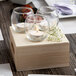 A group of Leola tea light candles in glass holders on a wooden table.