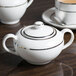 A white porcelain sugar bowl with silver double line trim and a lid.