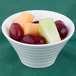An Arcoroc spiral porcelain bowl filled with fruit slices.