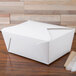 A white Fold-Pak Bio-Pak take-out box with a lid on a wood surface.
