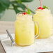 Two mason jars filled with yellow Del Monte Pineapple Juice with a cherry on top.