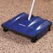 A blue and black Carlisle Duo-Sweeper floor sweeper on carpet.