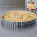 A tart with apples in it in a fluted Wilton quiche pan on a counter.