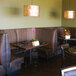 A 3/4 circle corner booth in a restaurant dining area with tables and chairs.