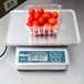 A plastic container of tomatoes on an Edlund digital portion scale.