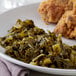 A plate of food with chicken and collard greens.