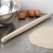 A maple wood Ateco French rolling pin and dough on a table.