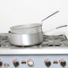 A Vollrath aluminum fry pot with a metal basket and metal handle on a stove.