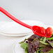 A red Cambro salad bar spoon on a plate of salad.
